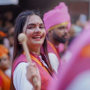 A joyful participant in a traditional festival parade in Pune, India, during Ganesh Chaturthi celebrations.
